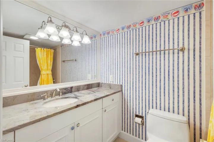 Bathroom featuring wallpapered walls and vanity