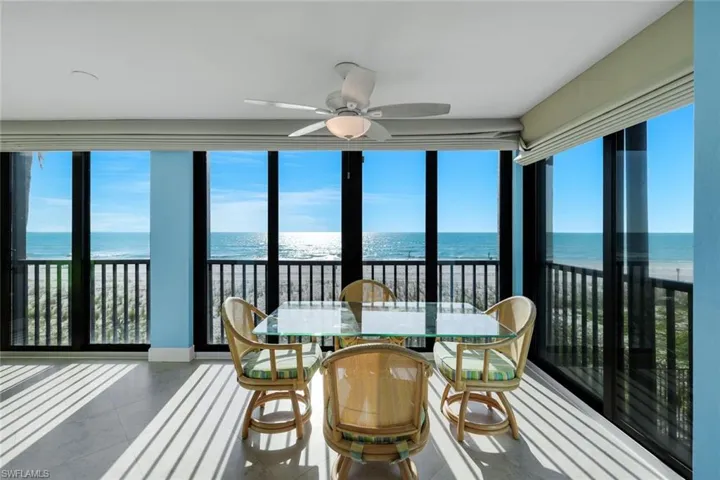Sunroom / solarium with view of water and beach, plenty of natural light, and floor to ceiling windows
