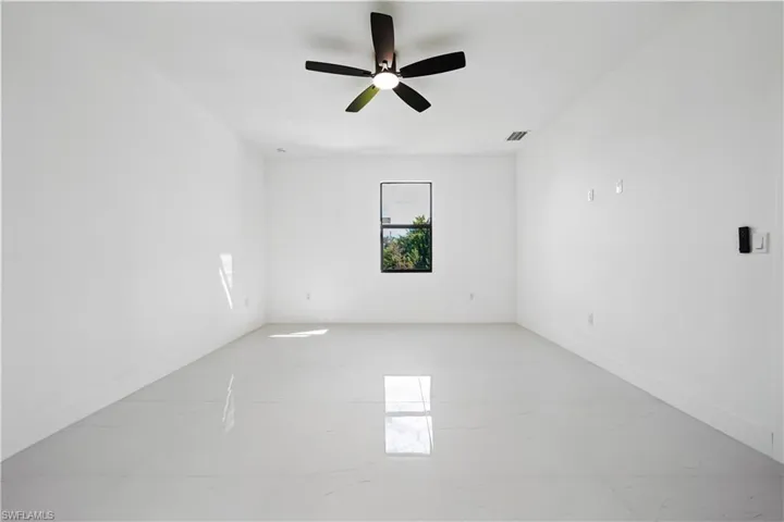 Empty room with light marble finish flooring and a ceiling fan