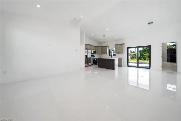 Unfurnished living room featuring lofted ceiling and recessed lighting