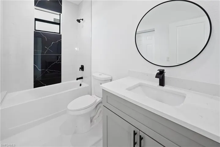 Bathroom featuring vanity and a combined bath / shower with marble appearance