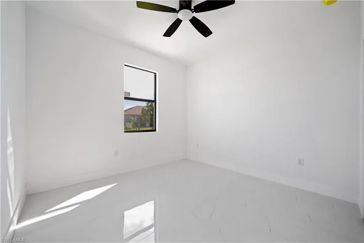 Spare room with light marble finish floors and a ceiling fan