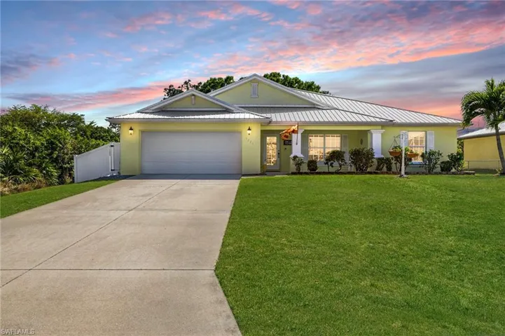 View of front of house featuring a standing seam roof, a yard, stucco siding, concrete driveway, and a garage