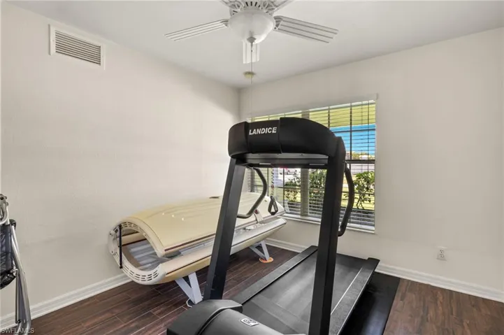Workout area featuring ceiling fan, visible vents, baseboards, and wood finished floors