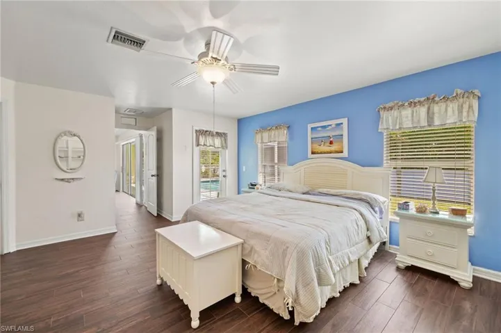 Bedroom featuring visible vents, ceiling fan, baseboards, dark wood-style floors, and access to outside