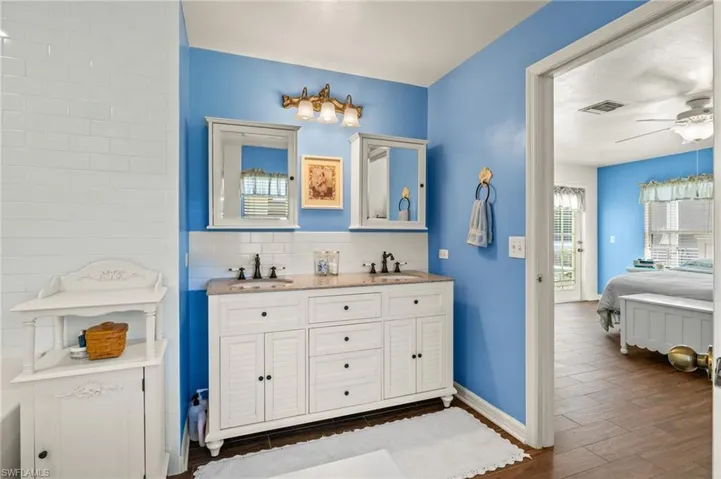 Ensuite bathroom featuring wood finished floors, visible vents, ensuite bathroom, and a sink