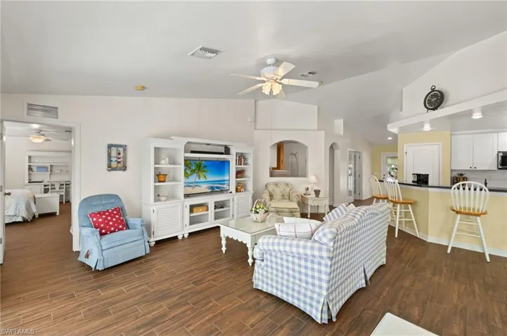 Living area with visible vents, lofted ceiling, wood finished floors, and a ceiling fan