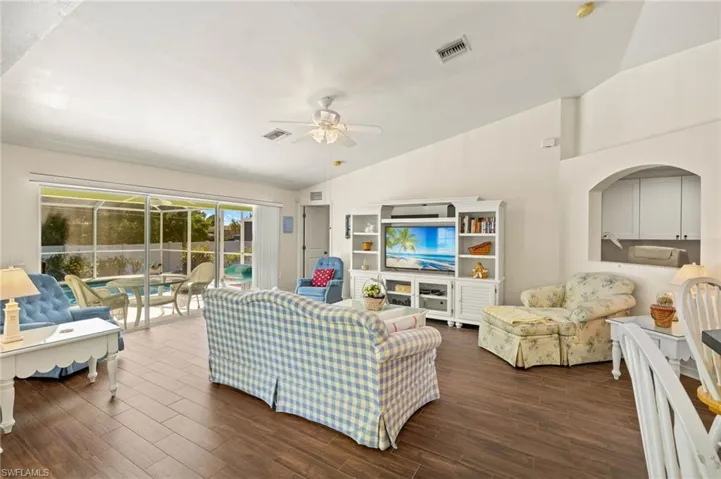Living area featuring visible vents, dark wood-type flooring, a ceiling fan, and vaulted ceiling