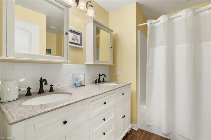 Full bath with tasteful backsplash, wood finished floors, shower / tub combo, and a sink