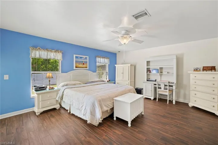 Bedroom featuring dark wood finished floors, baseboards, visible vents, and ceiling fan