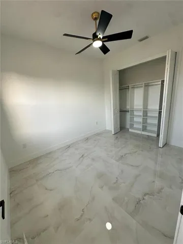 Unfurnished bedroom with ceiling fan, marble finish floor, baseboards, and visible vents