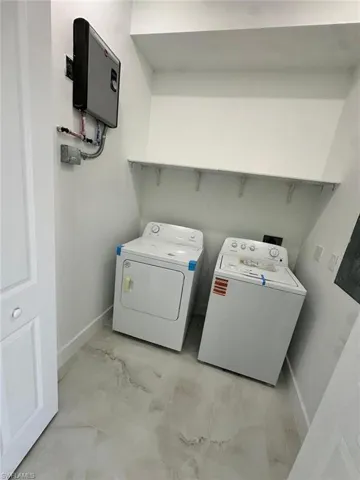 Laundry room featuring laundry area, marble finish floor, baseboards, and washing machine and dryer