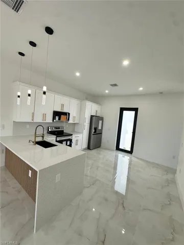 Kitchen featuring visible vents, recessed lighting, appliances with stainless steel finishes, marble finish floor, and a sink