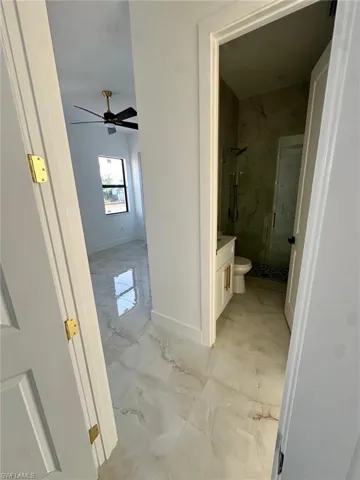 Full bathroom featuring baseboards, a ceiling fan, vanity, marble finish floor, and a stall shower