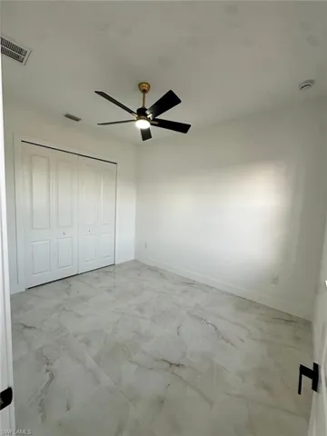 Unfurnished bedroom with visible vents, baseboards, marble finish floor, and a closet