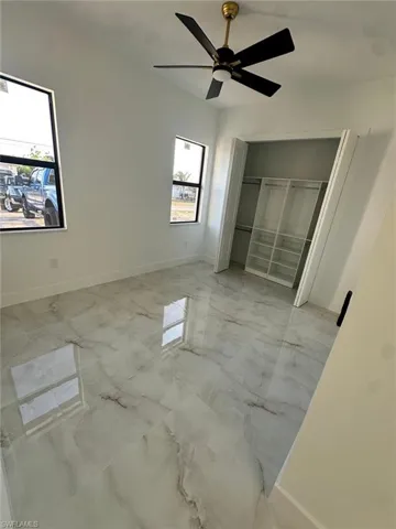 Unfurnished bedroom featuring baseboards, a ceiling fan, and marble finish floor