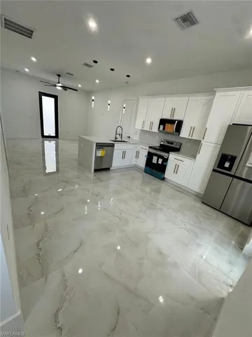 Kitchen featuring stainless steel appliances, open floor plan, visible vents, and marble finish floor