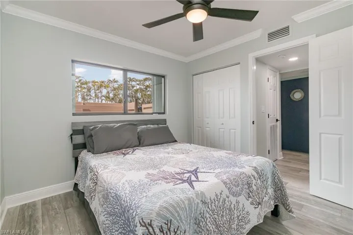 Bedroom featuring a closet, visible vents, light wood-style flooring, baseboards, and ornamental molding