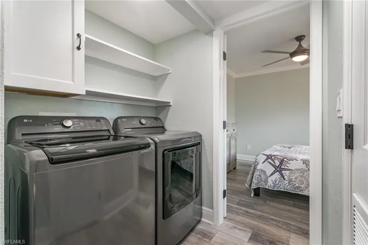Laundry room with a ceiling fan, wood finished floors, washing machine and clothes dryer, baseboards, and cabinet space
