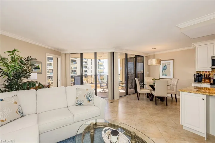 Living room with floor to ceiling windows, crown molding, and light tile patterned floors