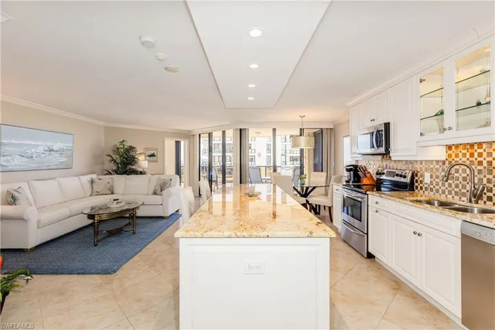 Kitchen with stainless steel appliances, a sink, a center island, tasteful backsplash, and crown molding
