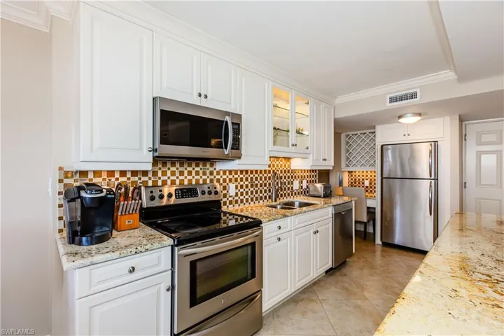 Kitchen with stainless steel appliances, visible vents, a sink, and decorative backsplash
