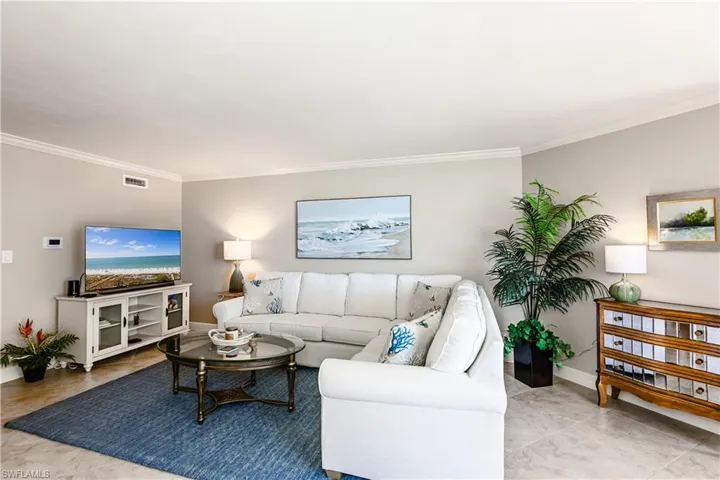 Living area with baseboards, visible vents, and crown molding