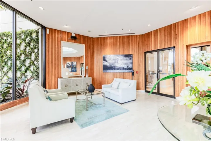 Living room with wooden walls, floor to ceiling windows, and recessed lighting