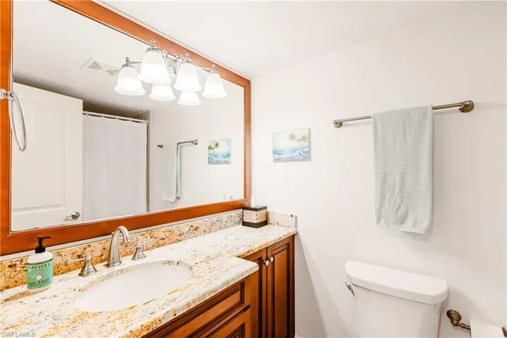 Bathroom featuring curtained shower, visible vents, vanity, and toilet