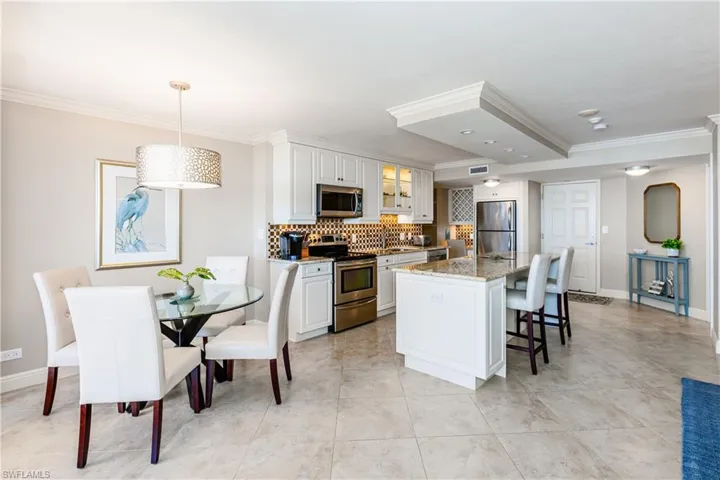 Kitchen with glass insert cabinets, a kitchen breakfast bar, stainless steel appliances, crown molding, and backsplash