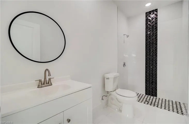 Bathroom with vanity, toilet, a tile shower, and tile patterned flooring