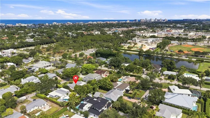 Residential neighborhood setting with mature trees, a nearby canal, and distant coastal line