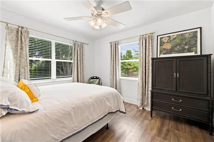 Wood-finish flooring, white ceiling fan with integrated lighting, window blinds, and white walls