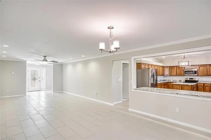 Unfurnished living room featuring a chandelier, recessed lighting, crown molding, light tile patterned floors, and a ceiling fan