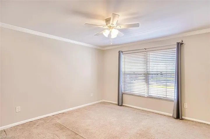 Spare room with light carpet, a ceiling fan, and crown molding