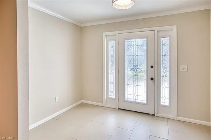 Foyer entrance with light tile patterned floors and ornamental molding