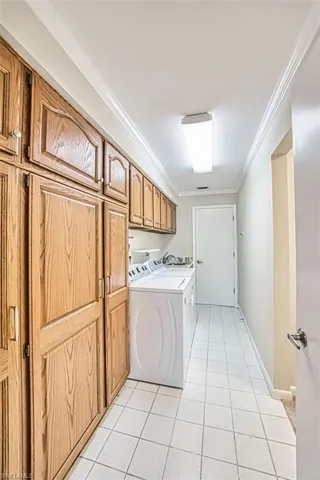 Laundry room featuring crown molding, separate washer and dryer, cabinet space, and light tile patterned floors