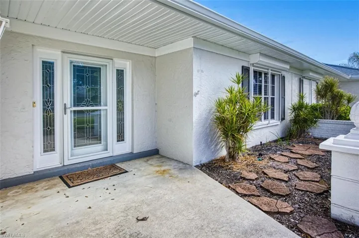 Property entrance with stucco siding and a patio