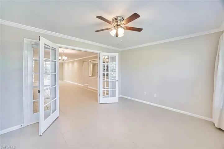 Unfurnished room featuring ornamental molding, a chandelier, ceiling fan, and french doors