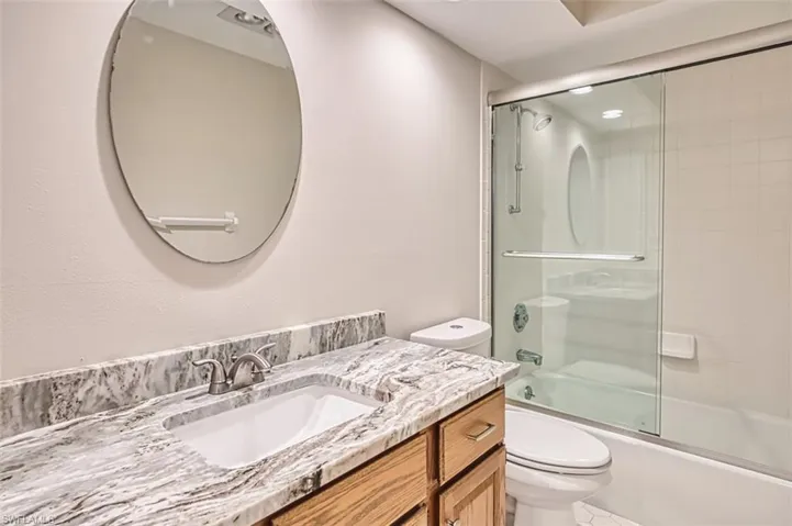 Full bath with combined bath / shower with glass door and vanity