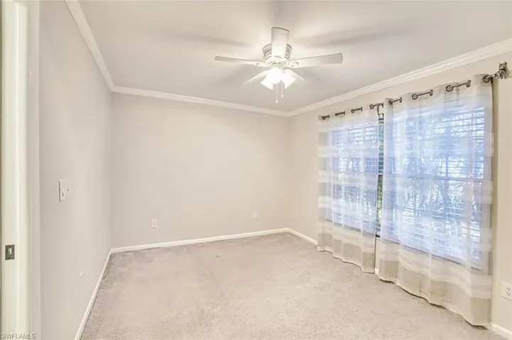 Carpeted empty room featuring crown molding and a ceiling fan