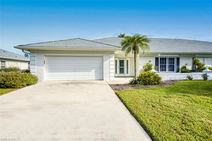 Ranch-style house featuring brick siding, roof with shingles, driveway, and a front yard