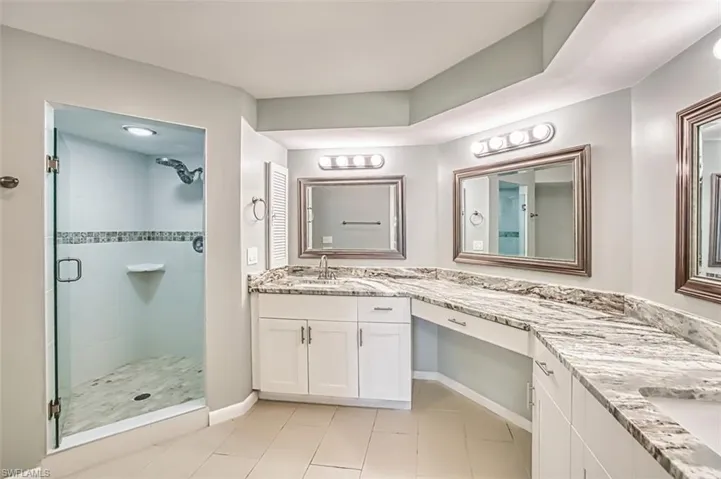 Bathroom with a shower stall, vanity, and light tile patterned flooring
