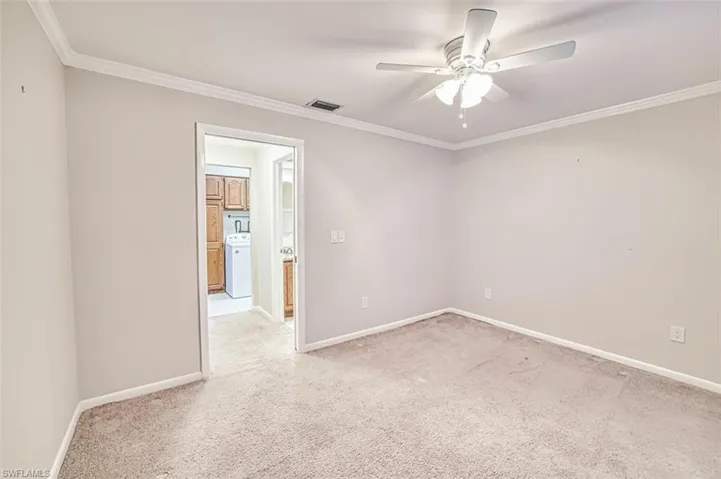 Unfurnished room with crown molding, light colored carpet, ceiling fan, and washer / dryer