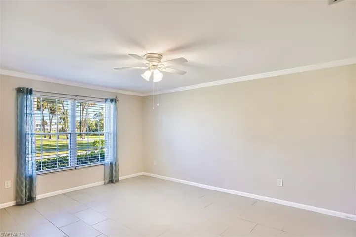 Spare room featuring crown molding, ceiling fan, and light tile patterned flooring