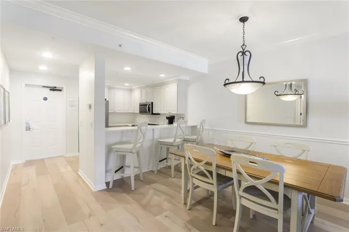 Dining space with light wood-type flooring and ornamental molding