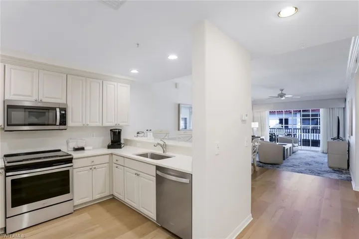 Kitchen featuring stainless steel appliances, light wood-type flooring, white cabinets, ceiling fan, and sink