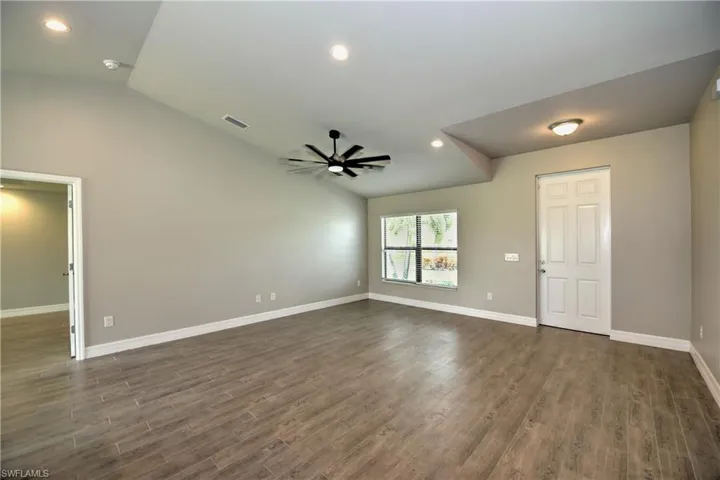 Empty room with vaulted ceiling, ceiling fan, and dark wood-type flooring