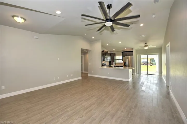 Unfurnished living room with ceiling fan, light wood-type flooring, and sink