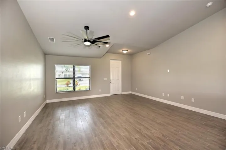 Unfurnished room with hardwood / wood-style floors, ceiling fan, and lofted ceiling